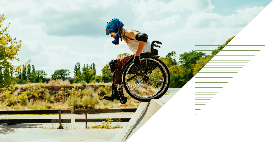a person in a wheelchair wears safety gear and prepares to drop into a halfpipe at a skate park